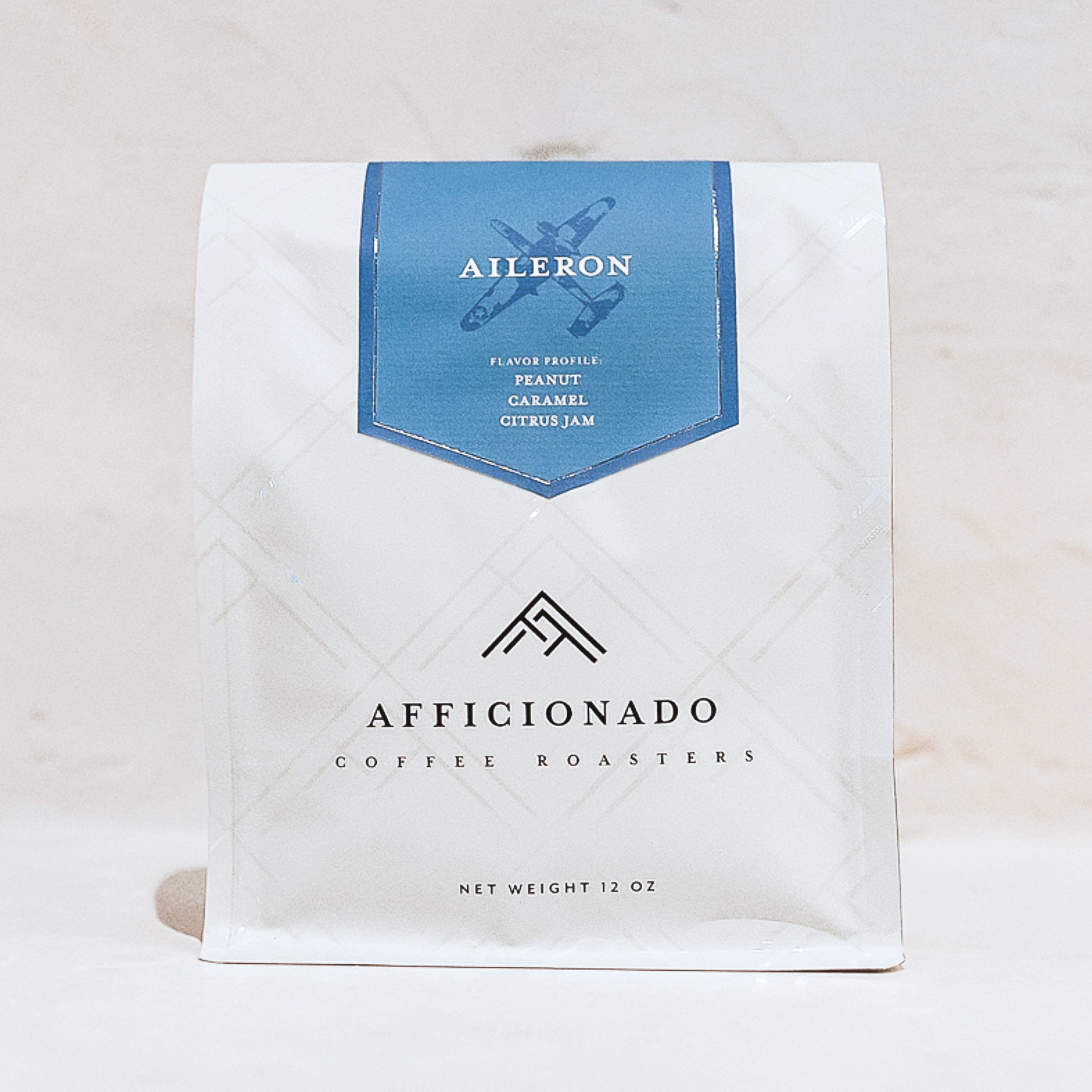 Aileron coffee, 12oz bag, blend, light blue label with airplane logo and flavor profile of peanut, caramel, and citrus jam.